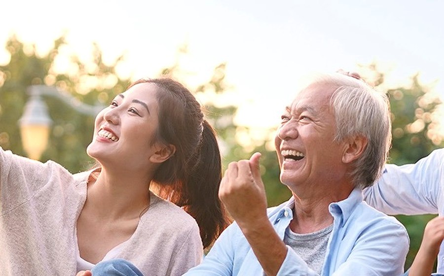 A young woman and an older man laughing together outdoors