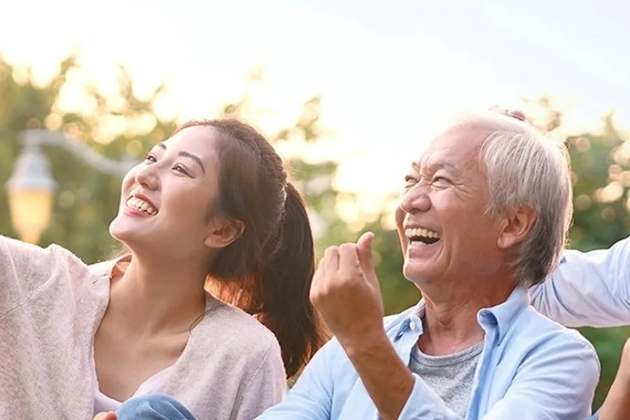 A young woman and an older man laughing together outdoors
