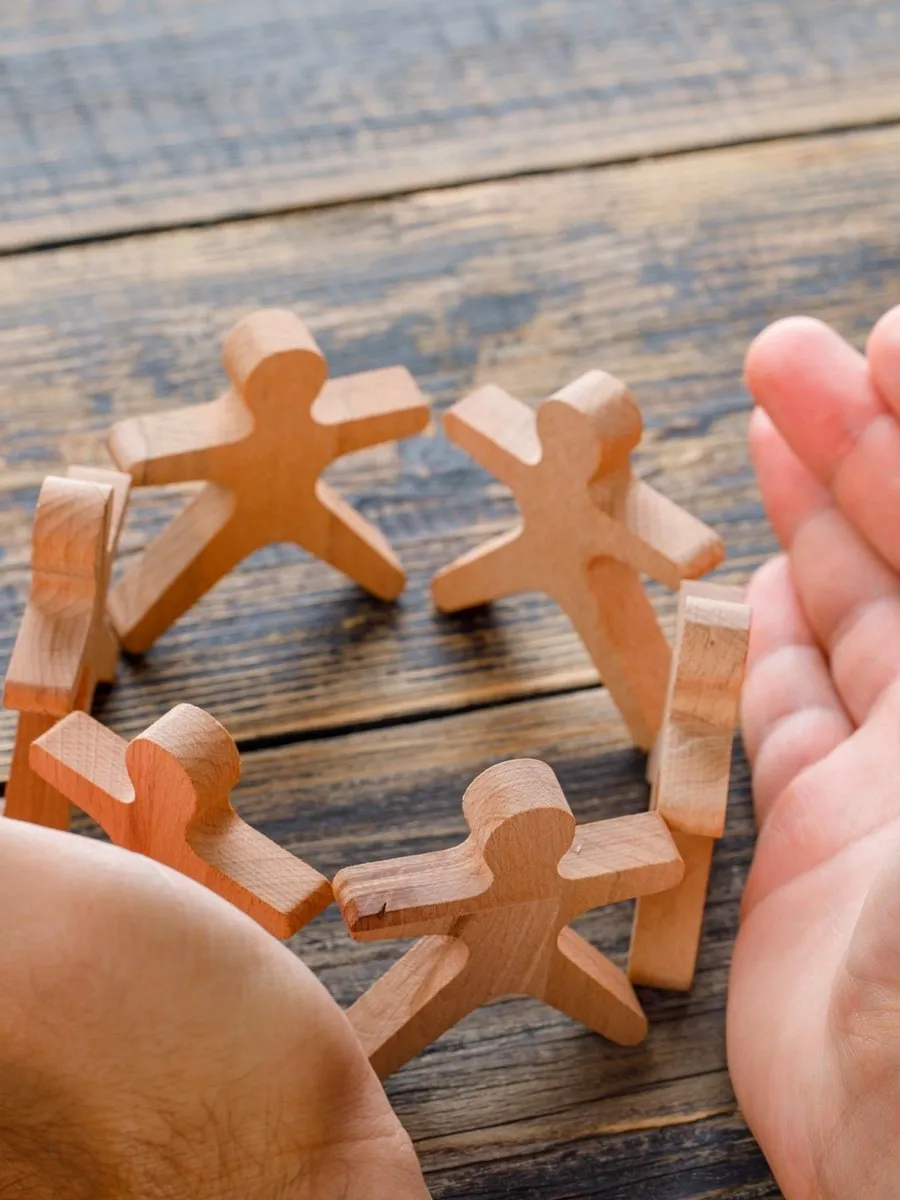 Wooden cut-out figures linked hand in hand on a table