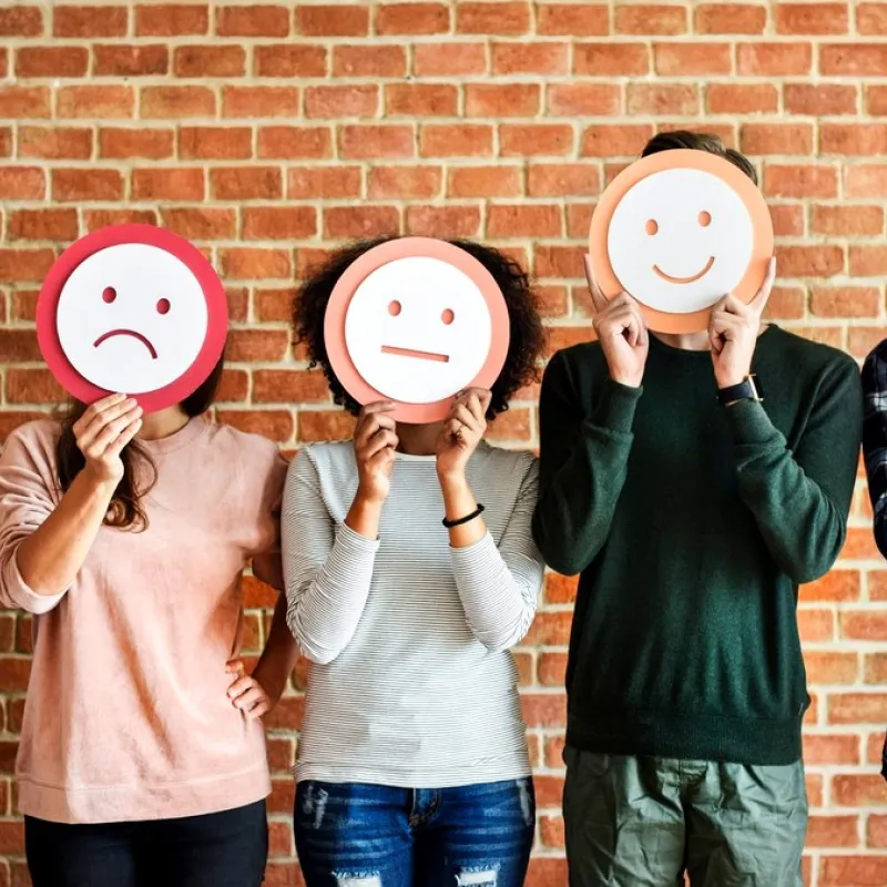 Five people holding paper faces that show different feelings