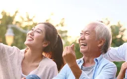 A young woman and an older man laughing together outdoors