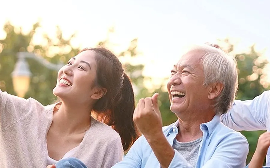 A young woman and an older man laughing together outdoors